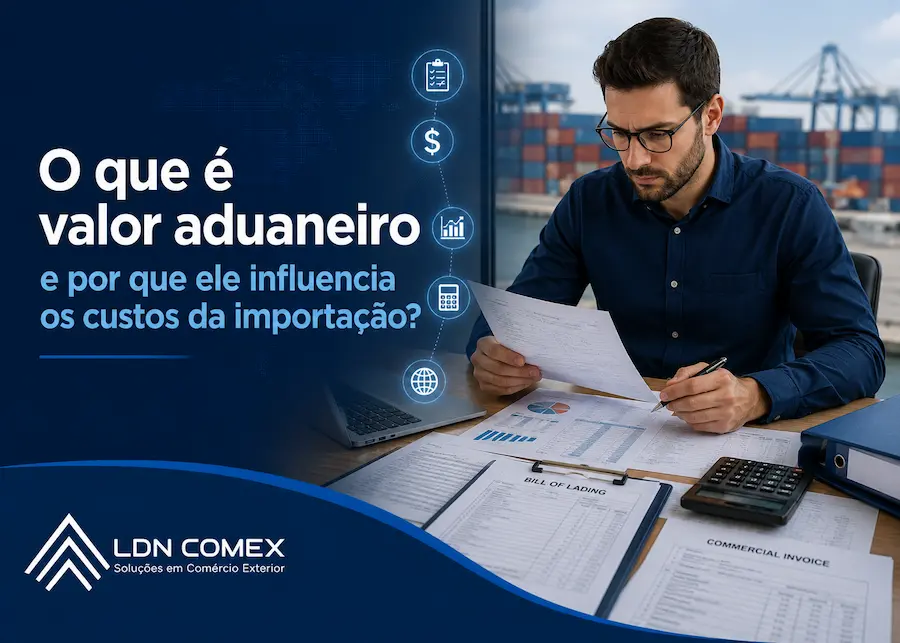 Profissional analisa documentos de importação e cálculos de valor aduaneiro em escritório, com terminal portuário ao fundo, representando a gestão de custos no comércio exterior.
